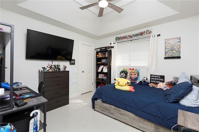 bedroom with light tile patterned floors, ceiling fan, and a tray ceiling