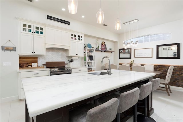 kitchen with pendant lighting, sink, white cabinets, decorative backsplash, and stainless steel electric range