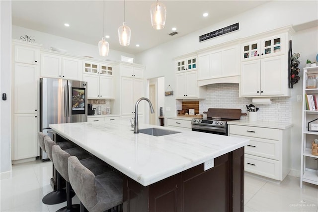 kitchen featuring appliances with stainless steel finishes, an island with sink, sink, and hanging light fixtures