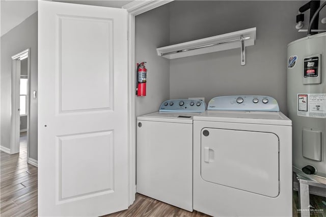 laundry room with washing machine and clothes dryer, electric water heater, and light hardwood / wood-style flooring