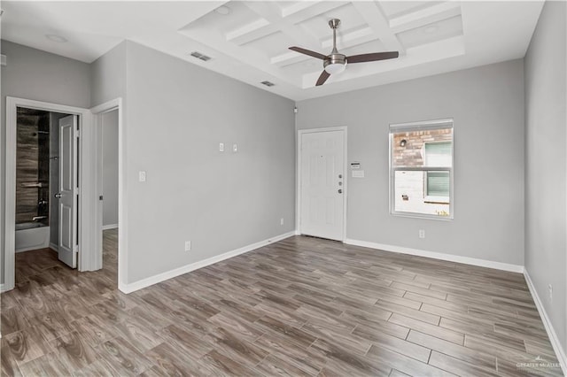 empty room with hardwood / wood-style floors, ceiling fan, coffered ceiling, and beam ceiling