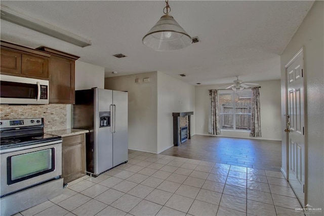 2800 Del Oro Dr, Mission, TX 78572 - kitchen featuring light countertops, ceiling fan, stainless steel appliances, a glass covered fireplace, and backsplash