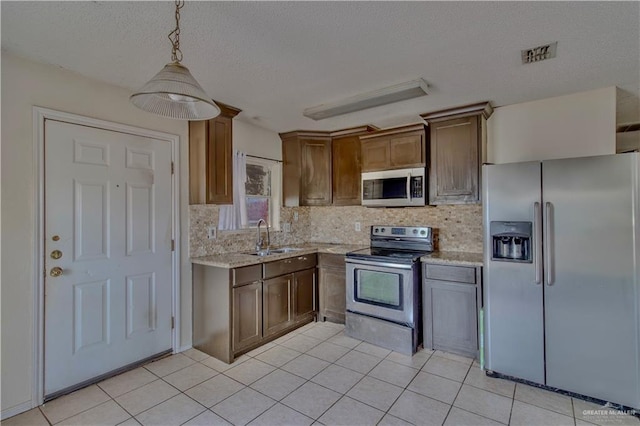 2800 Del Oro Dr, Mission, TX 78572 - kitchen featuring light tile patterned flooring, light stone counters, a sink, stainless steel appliances, and decorative backsplash