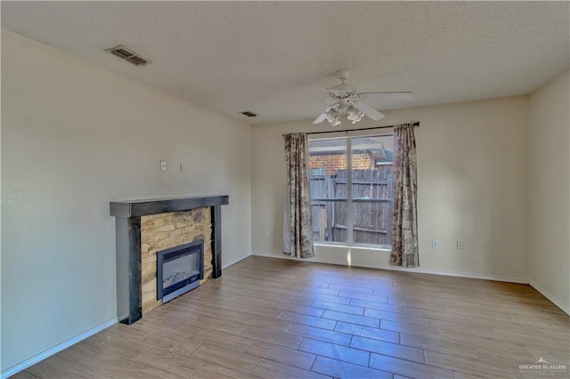 2800 Del Oro Dr, Mission, TX 78572 - unfurnished living room with a textured ceiling, visible vents, wood finished floors, a ceiling fan, and a stone fireplace