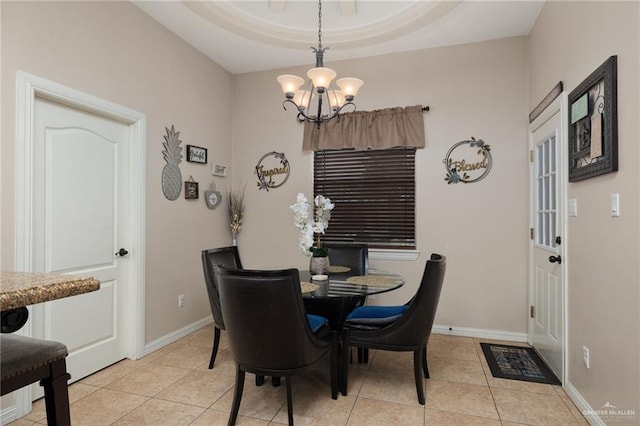 dining space featuring a notable chandelier, a raised ceiling, and light tile patterned floors