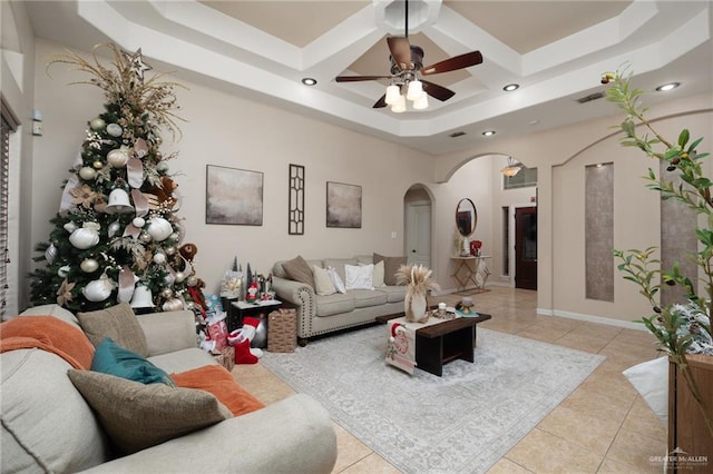 living room with a raised ceiling, ceiling fan, a towering ceiling, and light tile patterned flooring