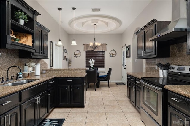 kitchen with stainless steel range with electric stovetop, stone counters, sink, wall chimney exhaust hood, and decorative light fixtures