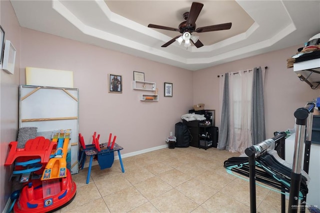 interior space featuring ceiling fan, a raised ceiling, and light tile patterned floors