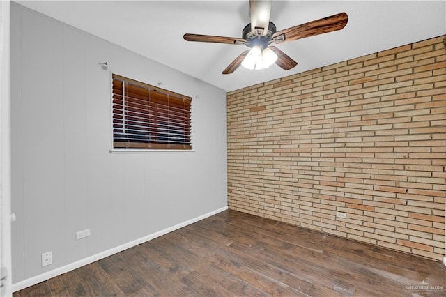 empty room with dark hardwood / wood-style flooring and brick wall