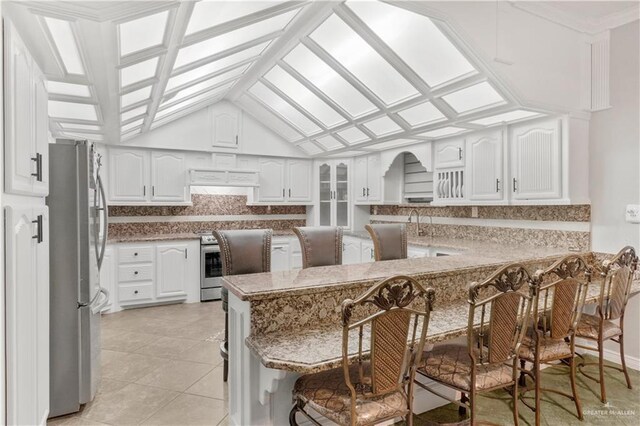5051 Iowa Rd, Mission, TX 78574 - kitchen with stainless steel appliances, tasteful backsplash, lofted ceiling, white cabinets, and light tile patterned floors