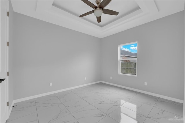 empty room featuring ceiling fan and a raised ceiling