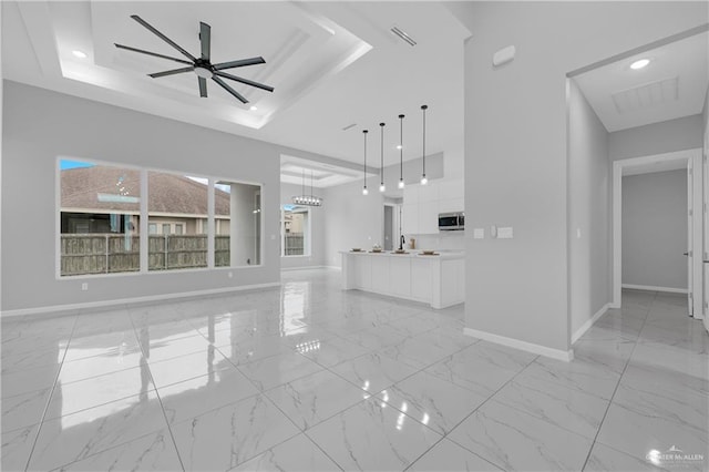 unfurnished living room with sink, a raised ceiling, and ceiling fan