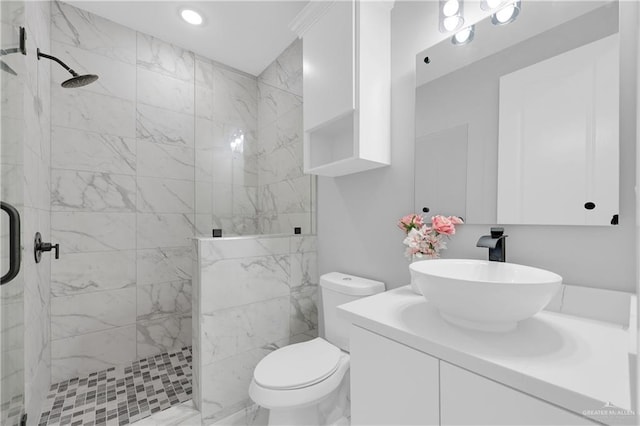 bathroom with tiled shower, vanity, and toilet