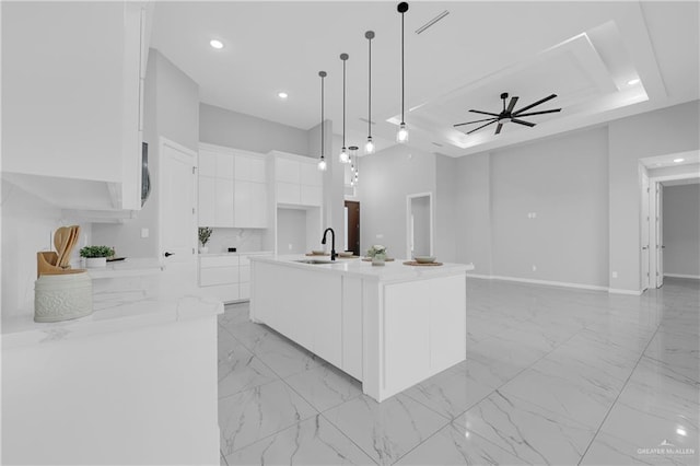 kitchen featuring pendant lighting, white cabinetry, sink, a large island with sink, and ceiling fan