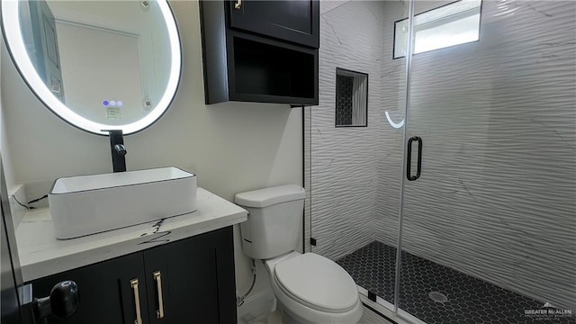 bathroom with a shower with door, vanity, and toilet