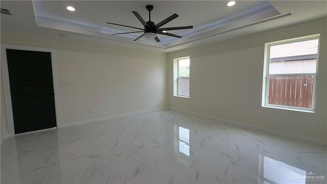 spare room featuring a tray ceiling, a wealth of natural light, and ceiling fan