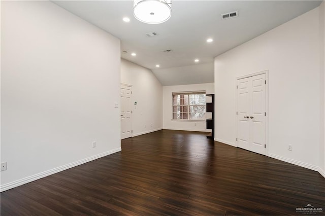 empty room with dark wood-type flooring and vaulted ceiling