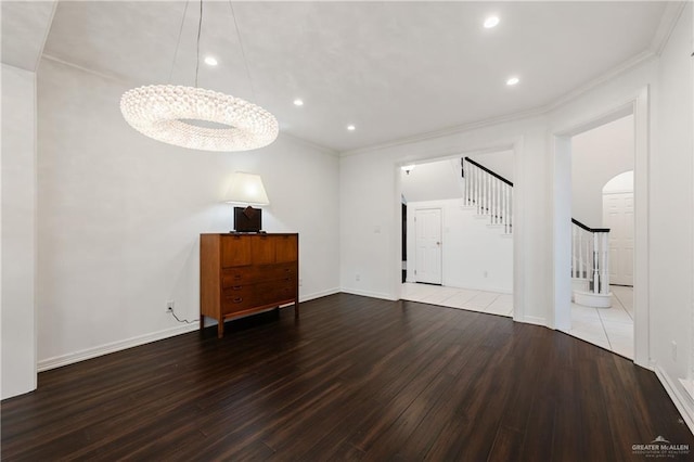 unfurnished living room with hardwood / wood-style floors, a notable chandelier, and crown molding