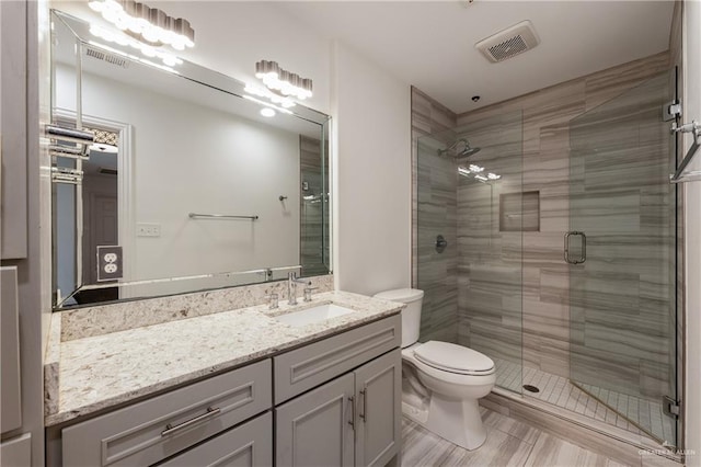 bathroom with vanity, a shower with shower door, and toilet