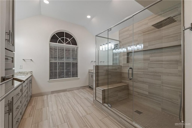 bathroom with vanity, a shower with door, and vaulted ceiling