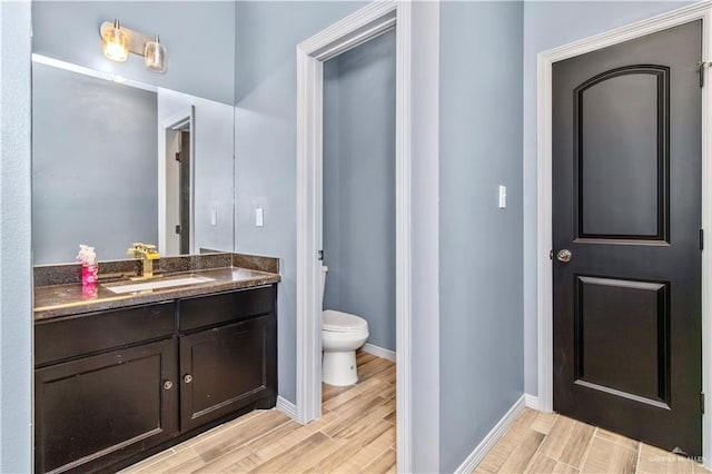 bathroom featuring wood-type flooring, vanity, and toilet