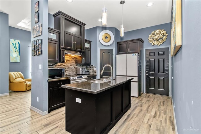 kitchen featuring backsplash, sink, a center island with sink, white fridge, and stainless steel electric range