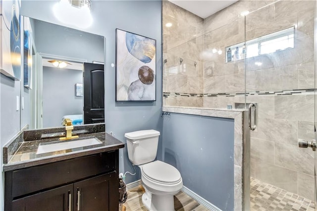 bathroom featuring ceiling fan, toilet, a shower with door, vanity, and hardwood / wood-style flooring