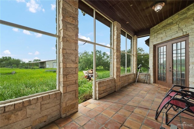 unfurnished sunroom with plenty of natural light, wood ceiling, and french doors