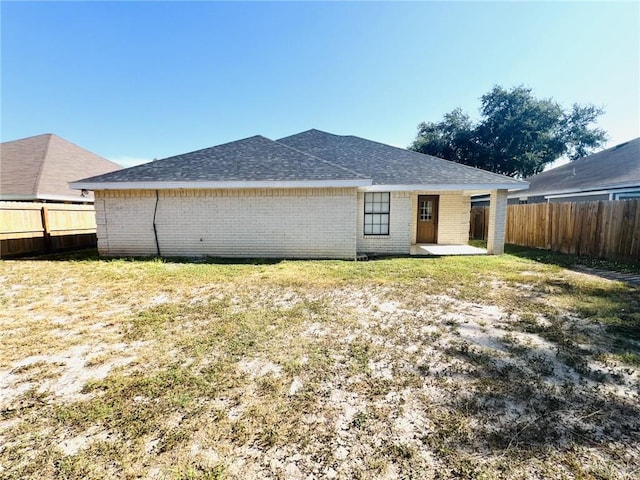 back of house with a lawn and a patio