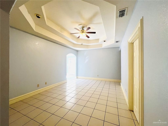 spare room featuring a tray ceiling, ceiling fan, and light tile patterned floors