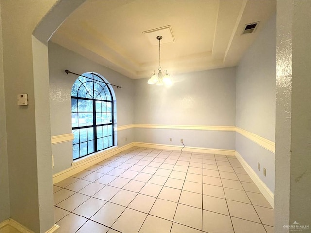 spare room with a tray ceiling, light tile patterned floors, and a notable chandelier