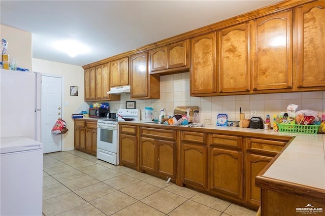 kitchen featuring decorative backsplash, white appliances, and light tile patterned flooring