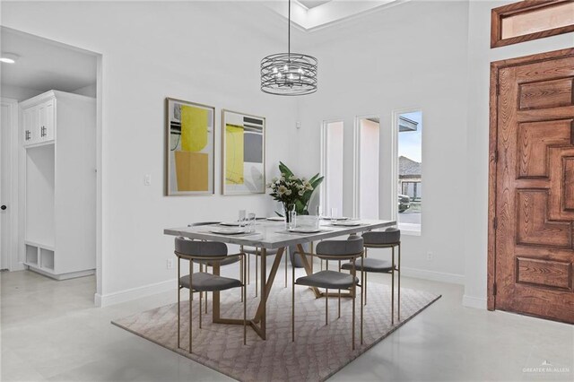 dining space with a chandelier, finished concrete flooring, and baseboards
