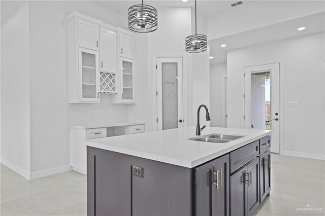 kitchen featuring white cabinetry, sink, a kitchen island with sink, and hanging light fixtures