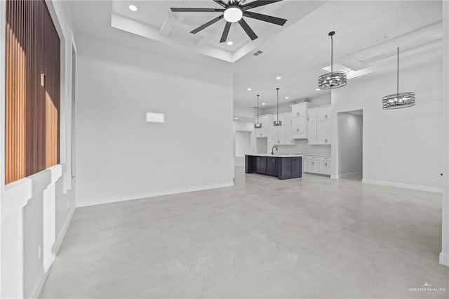 unfurnished living room featuring sink, ceiling fan, and a high ceiling