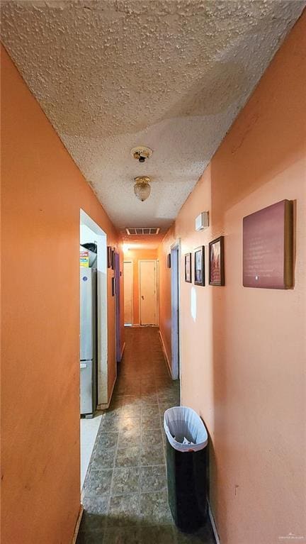 hallway featuring a textured ceiling and visible vents