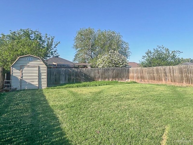 view of yard featuring a storage unit, a fenced backyard, and an outbuilding