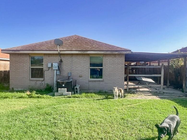 back of house with fence, a yard, central AC, and brick siding