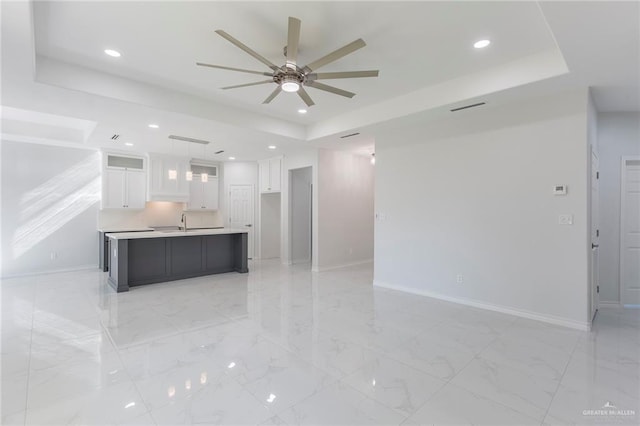 509 E Lorenzana St, Mercedes, TX 78570 - kitchen featuring white cabinets, ceiling fan, a raised ceiling, and baseboards