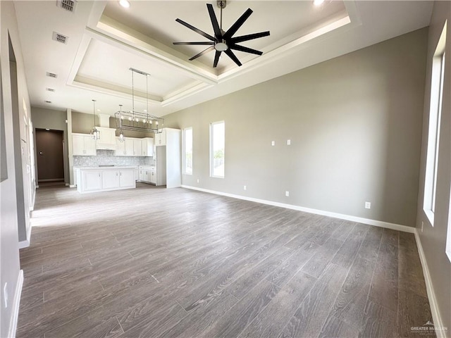 unfurnished living room featuring a tray ceiling, ceiling fan, and hardwood / wood-style flooring