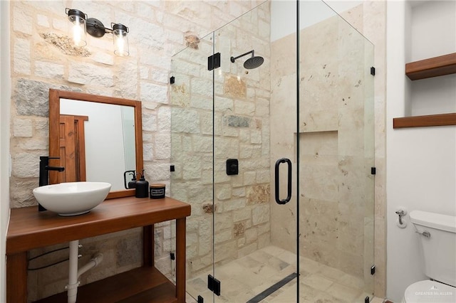 bathroom featuring sink, a shower with door, and toilet