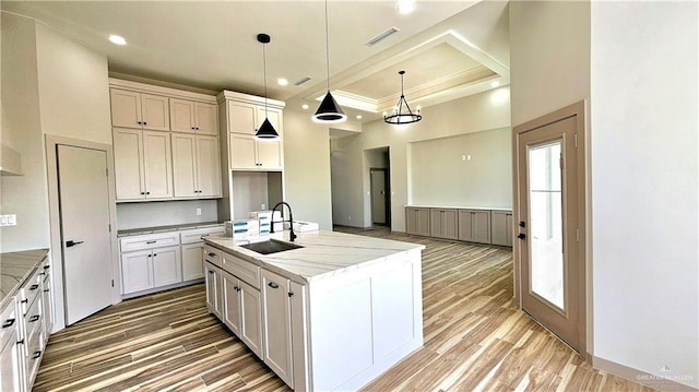 kitchen with light stone countertops, light wood-style flooring, visible vents, and a sink