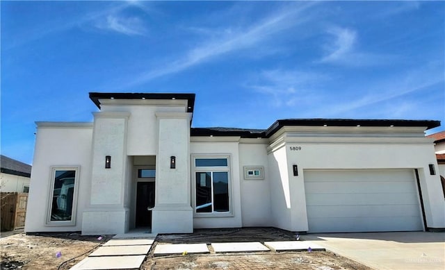 view of front of property featuring concrete driveway, an attached garage, and stucco siding