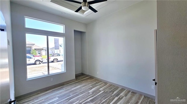 empty room featuring ceiling fan, baseboards, and wood finished floors