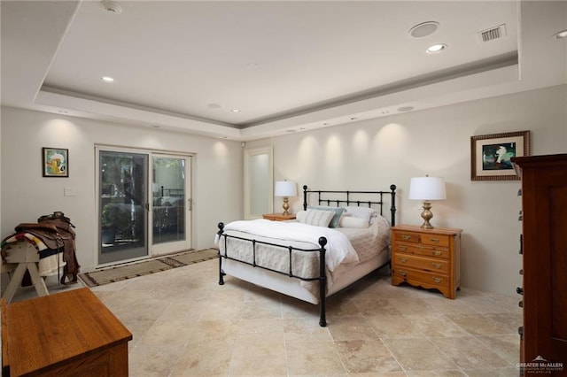 bedroom featuring access to exterior and a tray ceiling