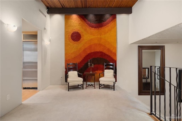 sitting room featuring beamed ceiling, carpet flooring, and wood ceiling