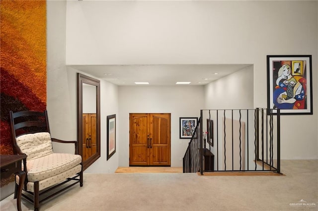 sitting room featuring a high ceiling and light carpet