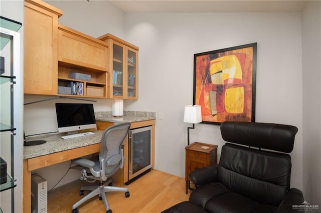 office area featuring built in desk, beverage cooler, and light wood-type flooring