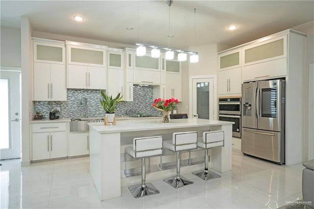 2008 S Erica St, Pharr, TX 78577 - kitchen with appliances with stainless steel finishes, tasteful backsplash, a breakfast bar area, light countertops, and white cabinetry