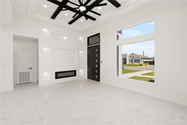 unfurnished living room featuring a glass covered fireplace, recessed lighting, marble finish floor, and a towering ceiling